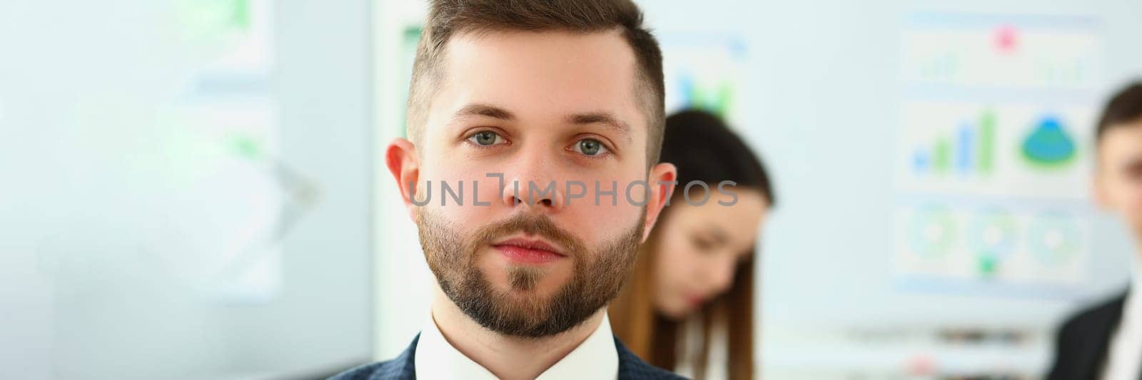 Portrait of serious businessman in background business partners colleagues by kuprevich