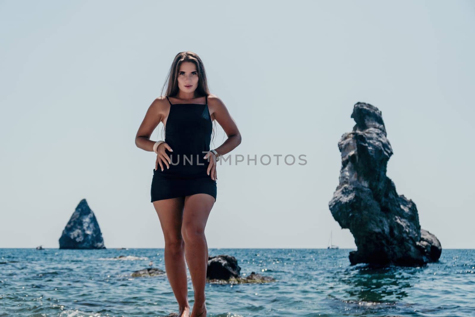 Woman summer travel sea. Happy tourist in hat enjoy taking picture outdoors for memories. Woman traveler posing on the beach at sea surrounded by volcanic mountains, sharing travel adventure journey by panophotograph