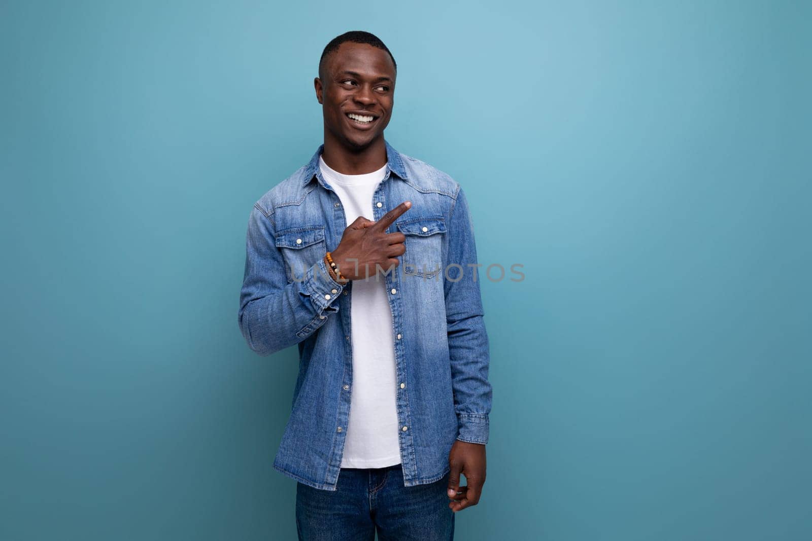 smart young american man in denim jacket is inspired by an idea on a blue background with copy space.