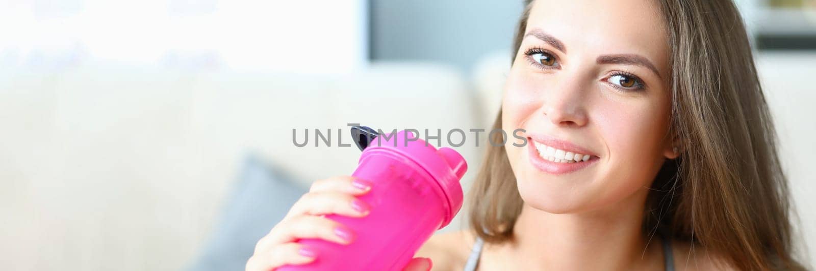 Portrait of sporty smiling beautiful woman with bottle of water. Sports and fat intake during exercise