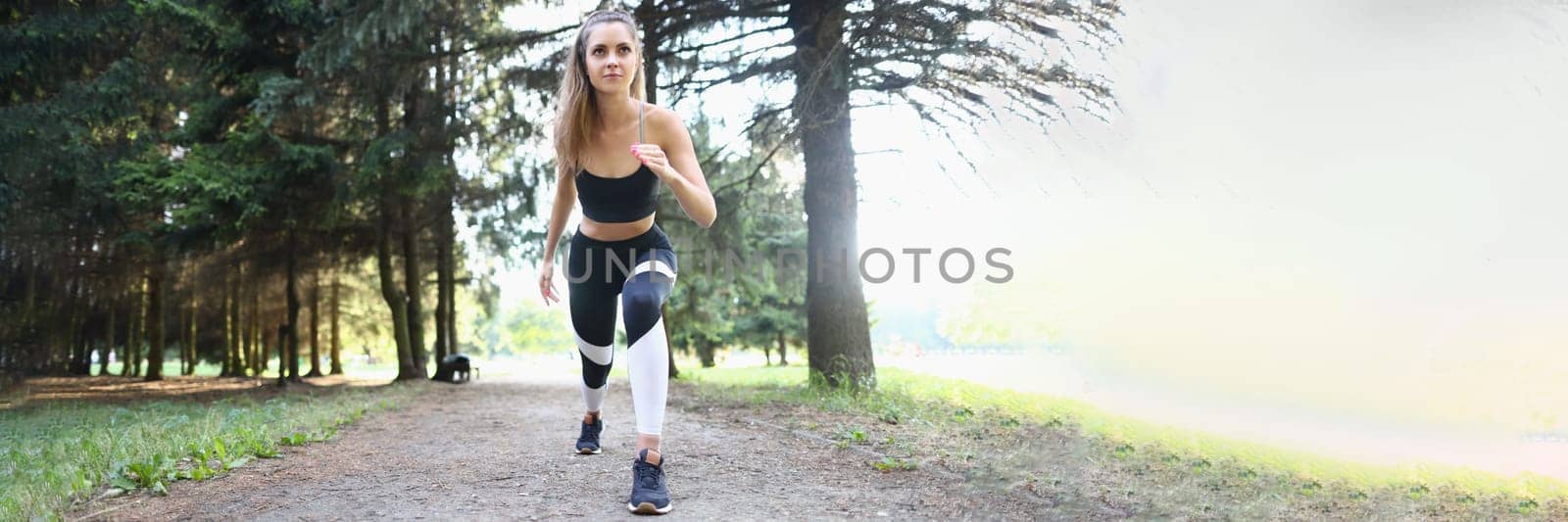 Beautiful athletic young woman starts jogging in park. Morning or evening run concept