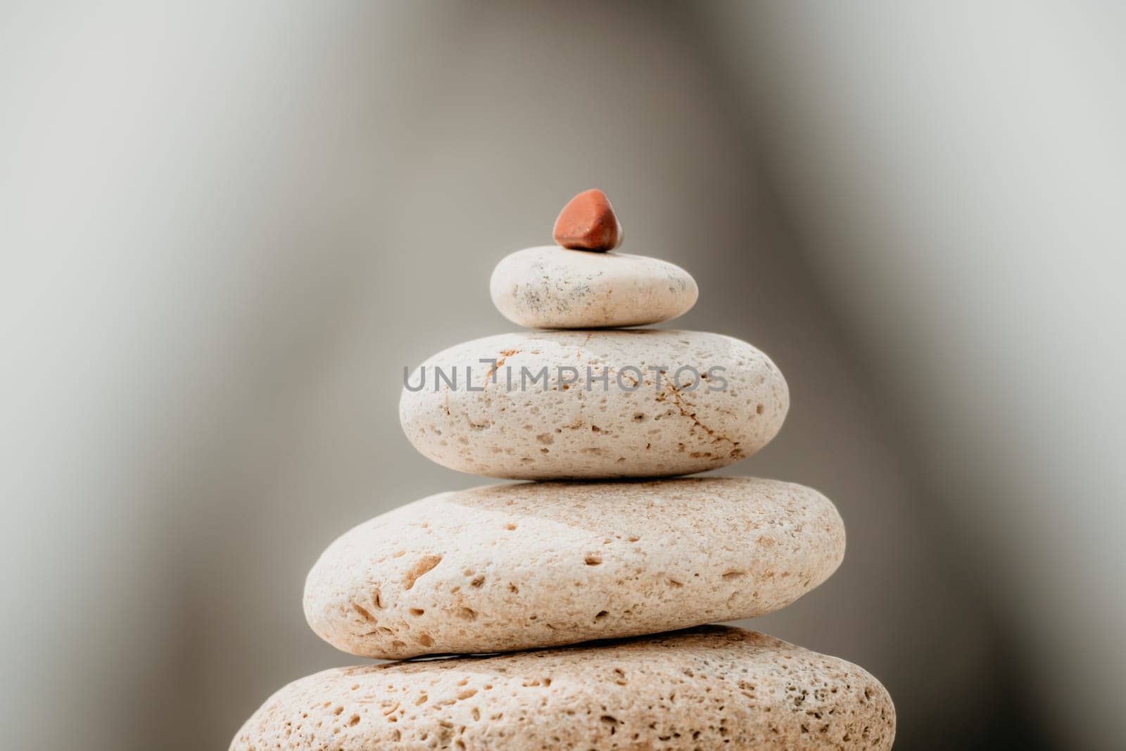 balanced rock pyramid stands tall on sea pebble beach. Selective focus highlights zen stones on the beach, evoking feelings of calm, harmony, and balance. Perfect for meditation or spa concepts. by panophotograph