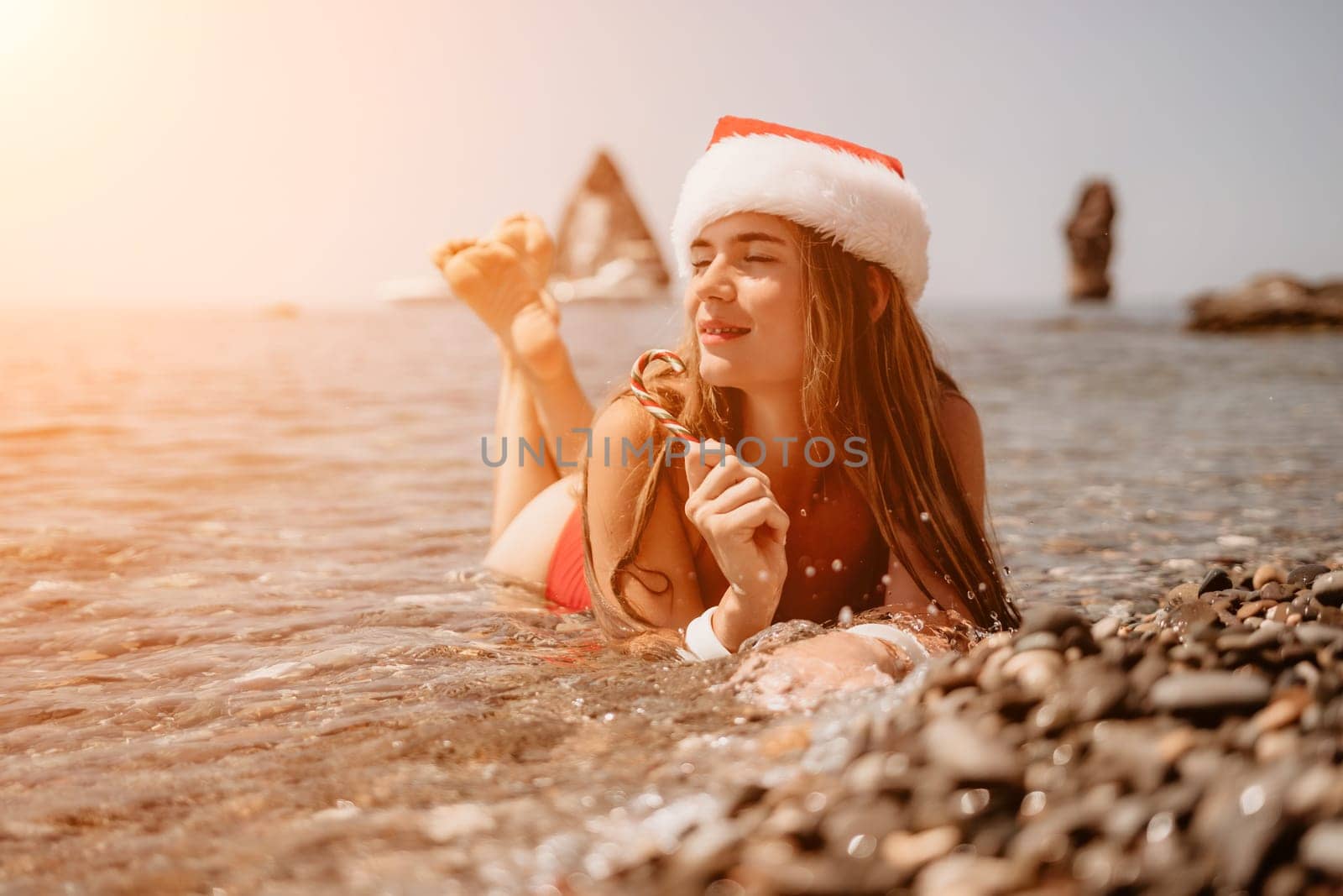 Woman travel sea. Happy tourist enjoy taking picture on the beach for memories. Woman traveler in Santa hat looks at camera on the sea bay, sharing travel adventure journey by panophotograph