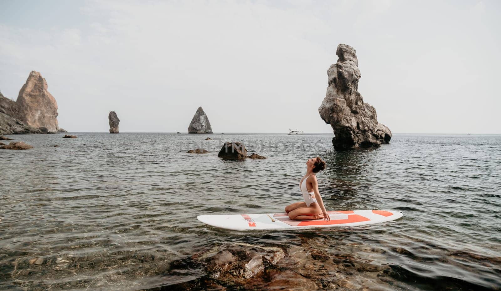 Woman sup yoga. Happy sporty woman practising yoga pilates on paddle sup surfboard. Female stretching doing workout on sea water. Modern individual female hipster outdoor summer sport activity. by panophotograph