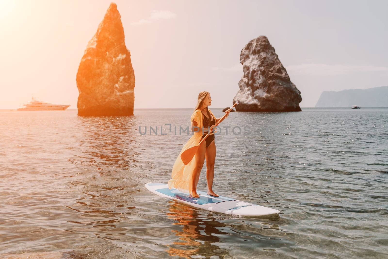 Woman sea sup. Close up portrait of happy young caucasian woman with long hair looking at camera and smiling. Cute woman portrait in bikini posing on sup board in the sea by panophotograph