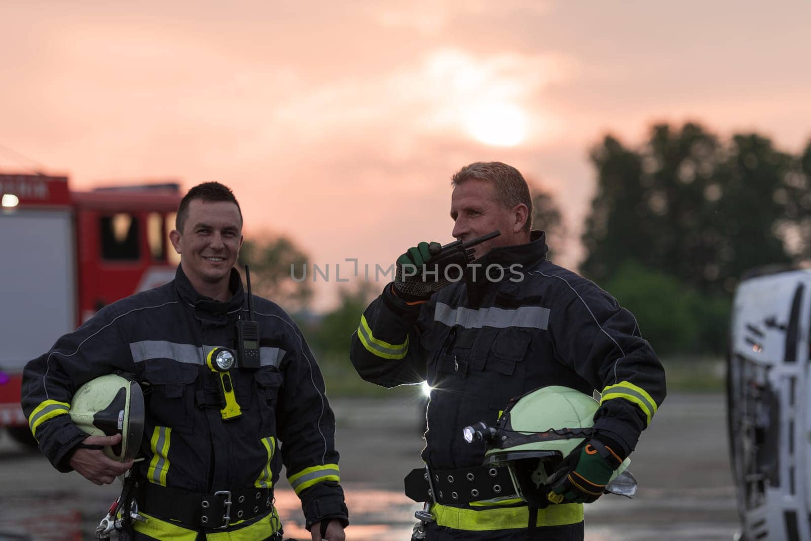 fireman using walkie talkie at rescue action fire truck and fireman's team in background. High quality photo