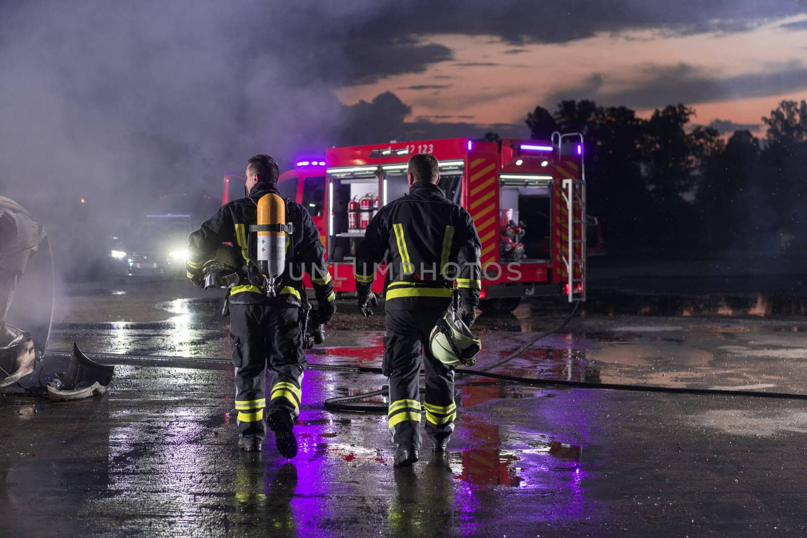 Brave Firefighters Team Walking to the Camera. In Background Paramedics and Firemen Rescue Team Fight Fire in Car Accident, Insurance and Save Peoples Lives concept. High quality photo