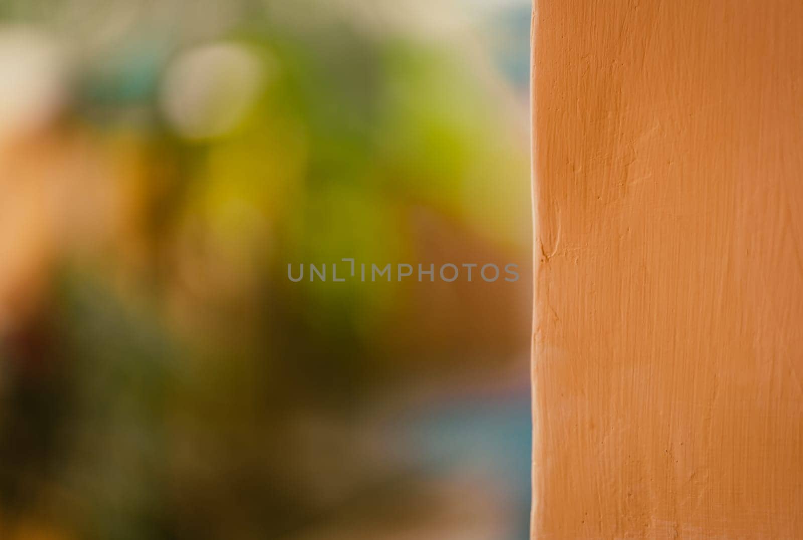 Close up shot of orange color painted wall with a blurred natural bokeh background for advertising slogan.