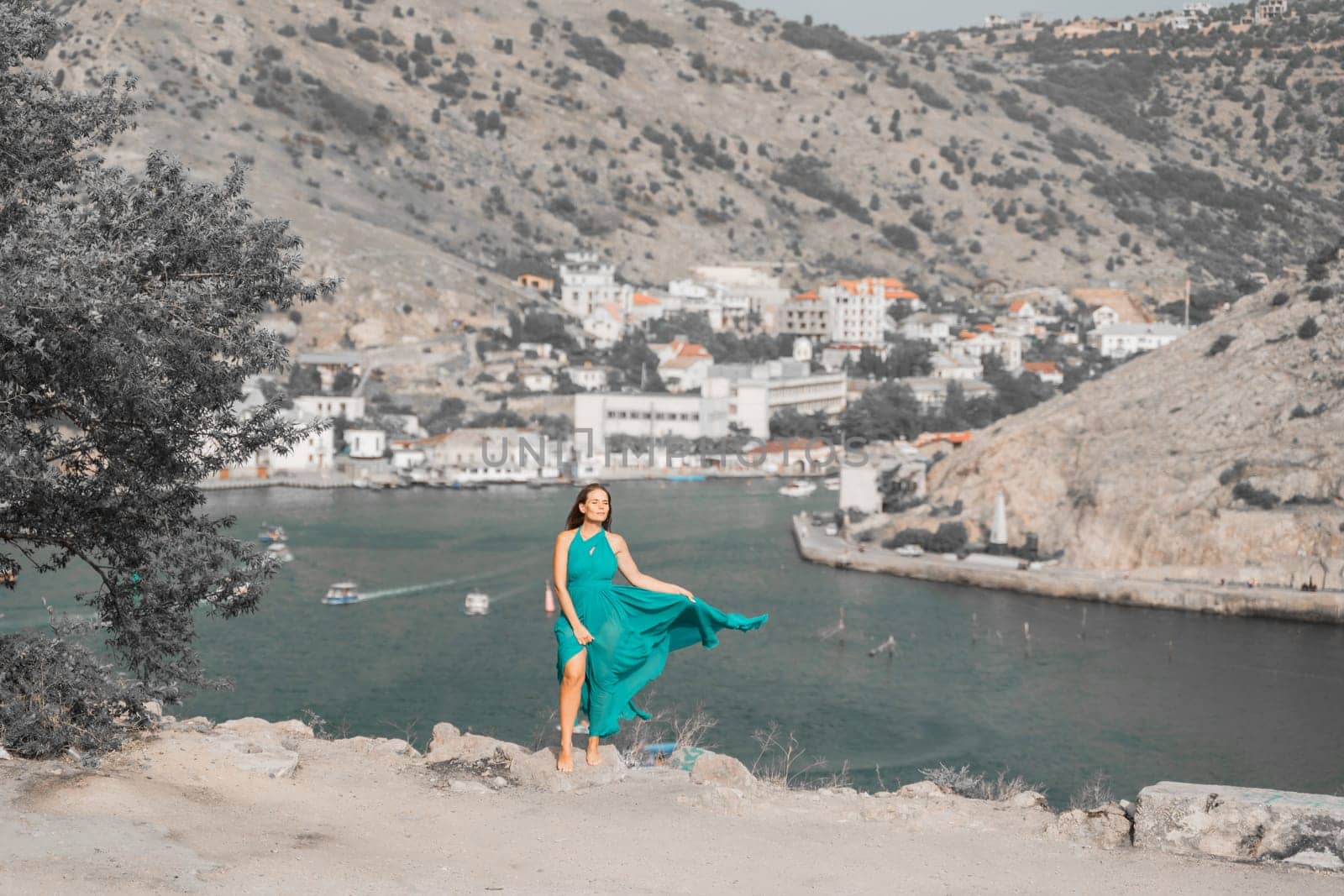 Woman sea green dress. Side view a happy woman with long hair in a long mint dress posing on a beach with calm sea bokeh lights on sunny day. Girl on the nature on blue sky background. by Matiunina