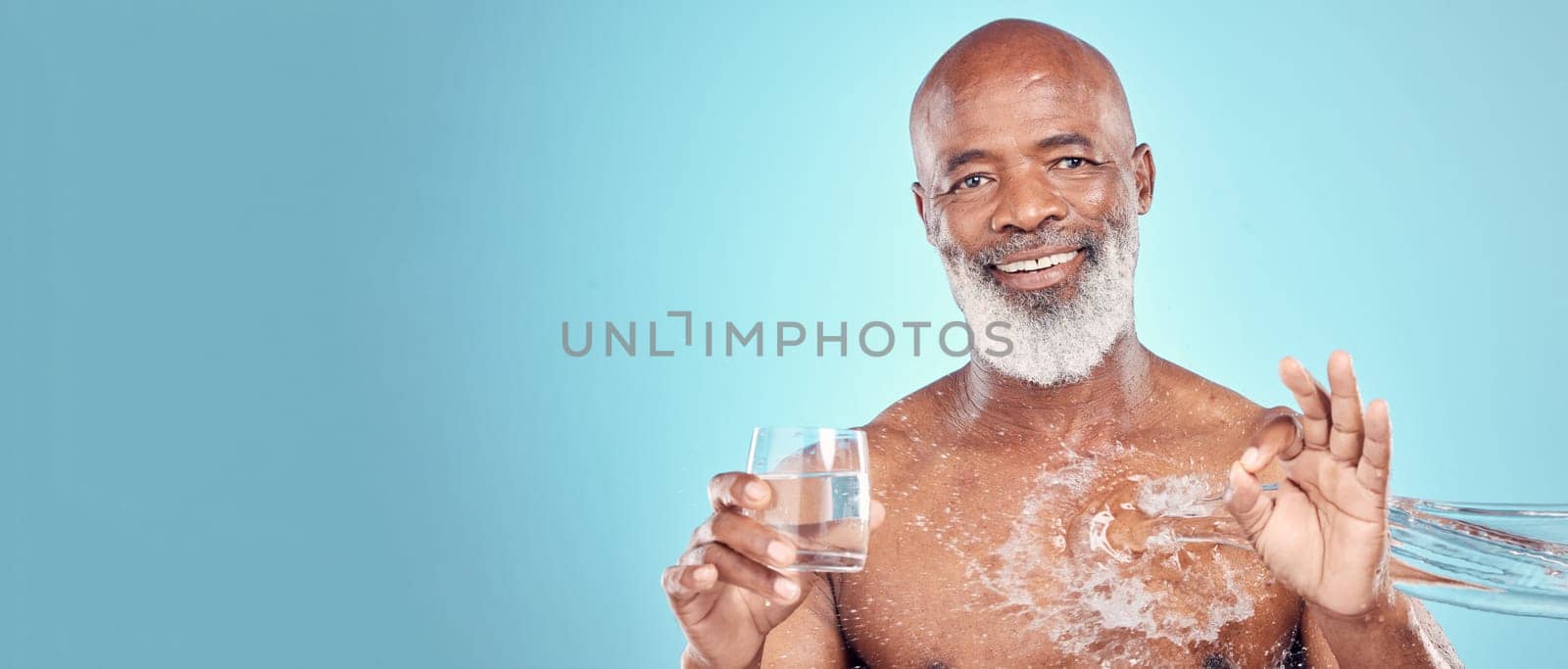 Water splash, portrait and senior man in a studio with a glass of aqua and a ok hand gesture. Health, wellness and happy elderly African male with sign language by a blue background with mockup space.