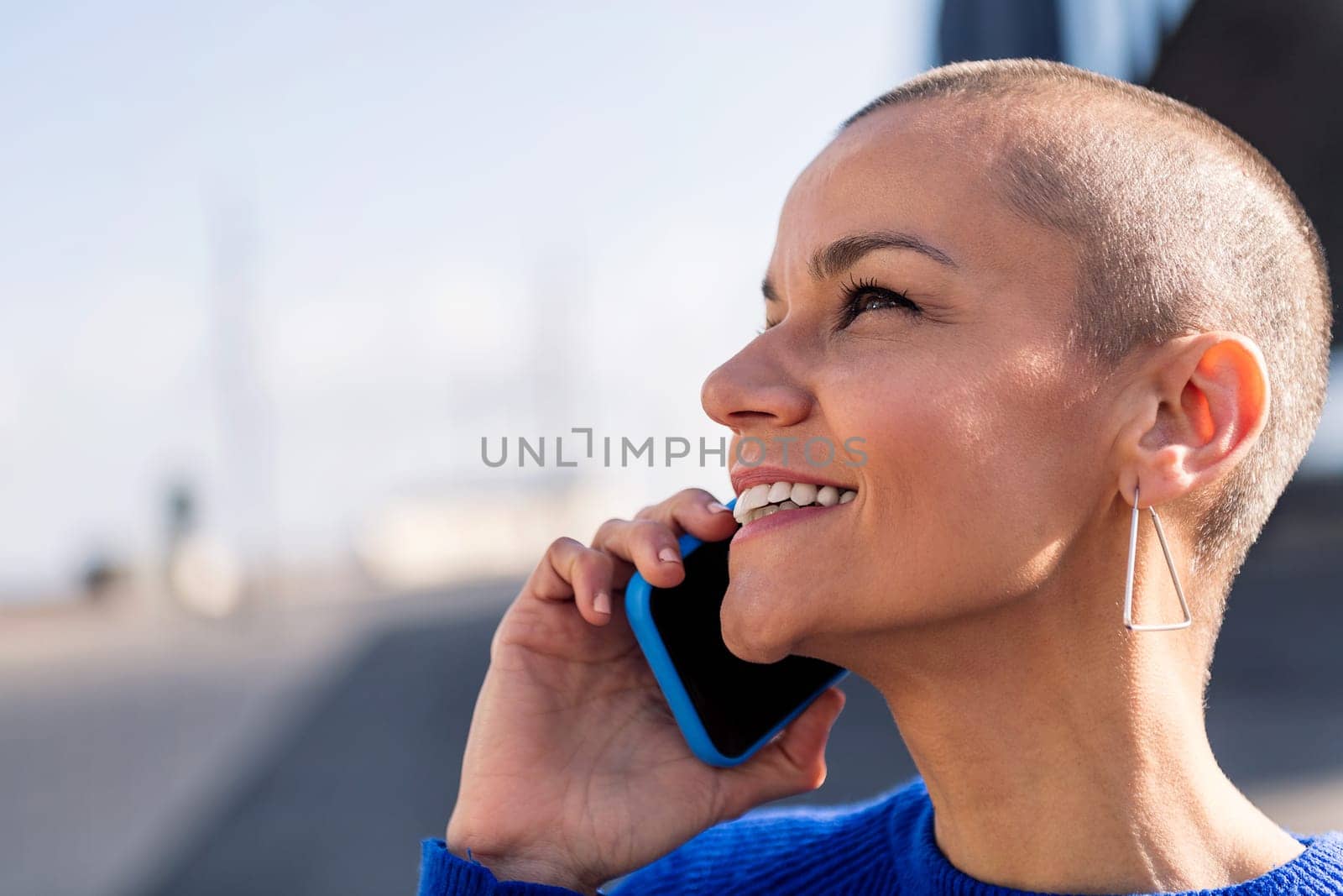 portrait of a confident young woman with buzz cut talking happy on mobile phone, concept or modern lifestyle and technology of communication, copy space for text