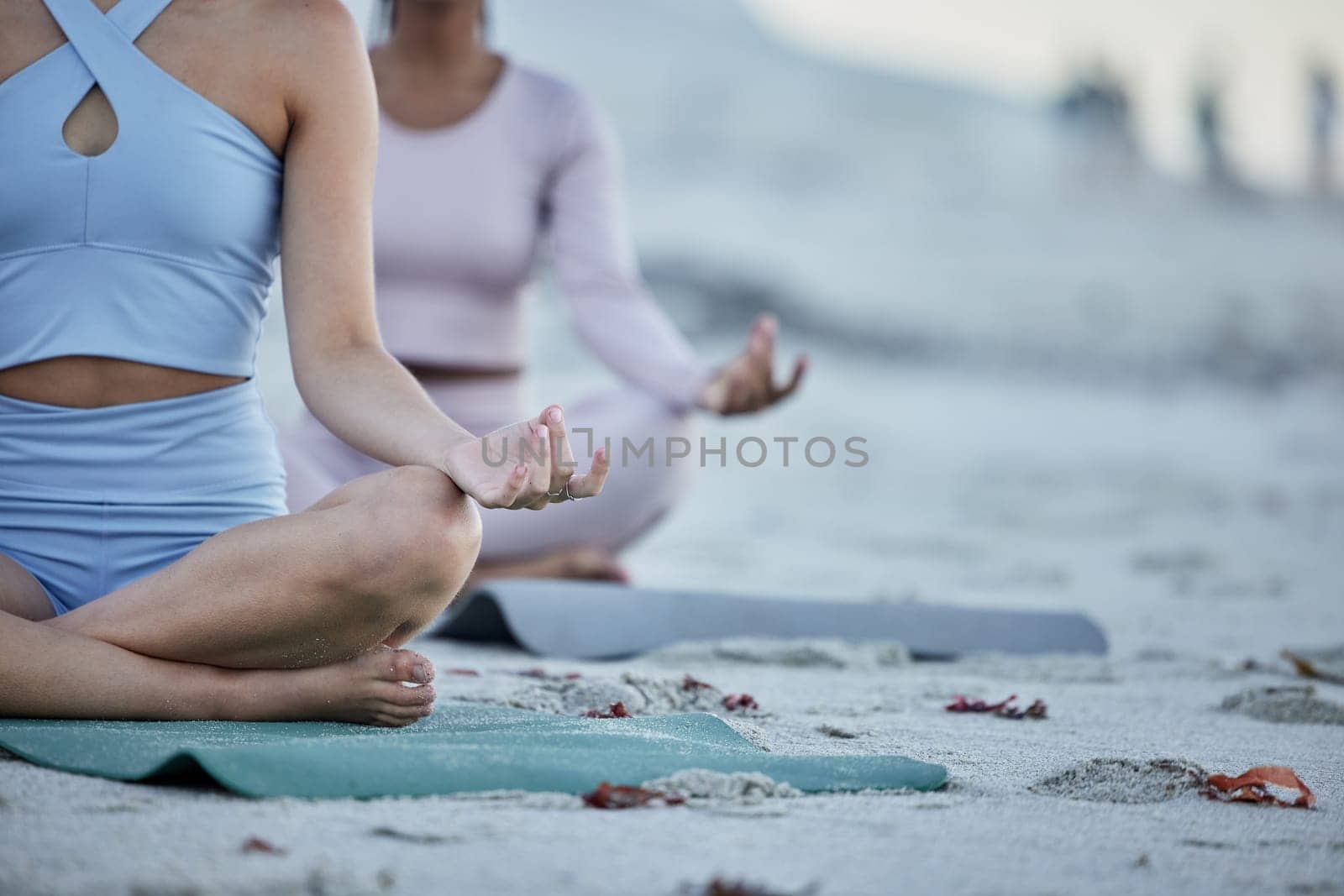 Hands, yoga and friends on the beach for spiritual health and wellness workout or exercise. Training, friendship and yogi women meditating on yoga mats on the seaside sand for grattitude and mindset.