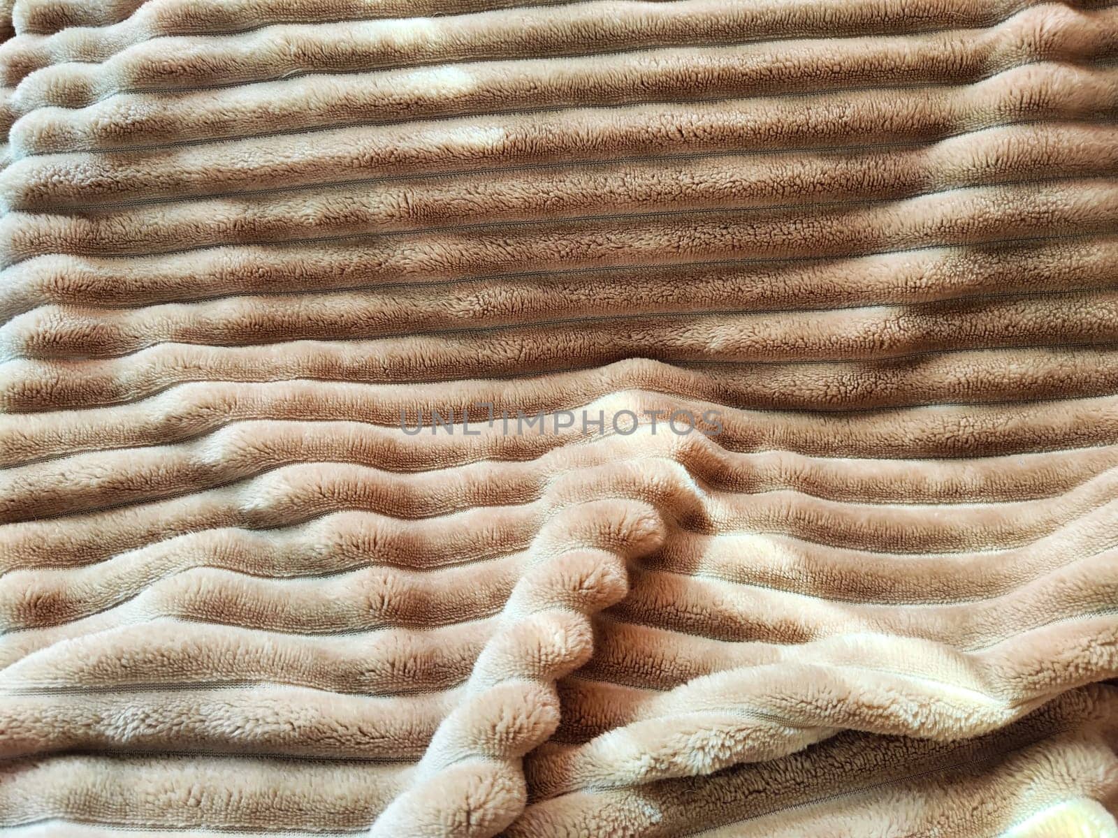 Closeup soft, fluffy sleeping beige blanket or plaid. Crumpled fabric. Abstract background, texture with frame. Partial focus