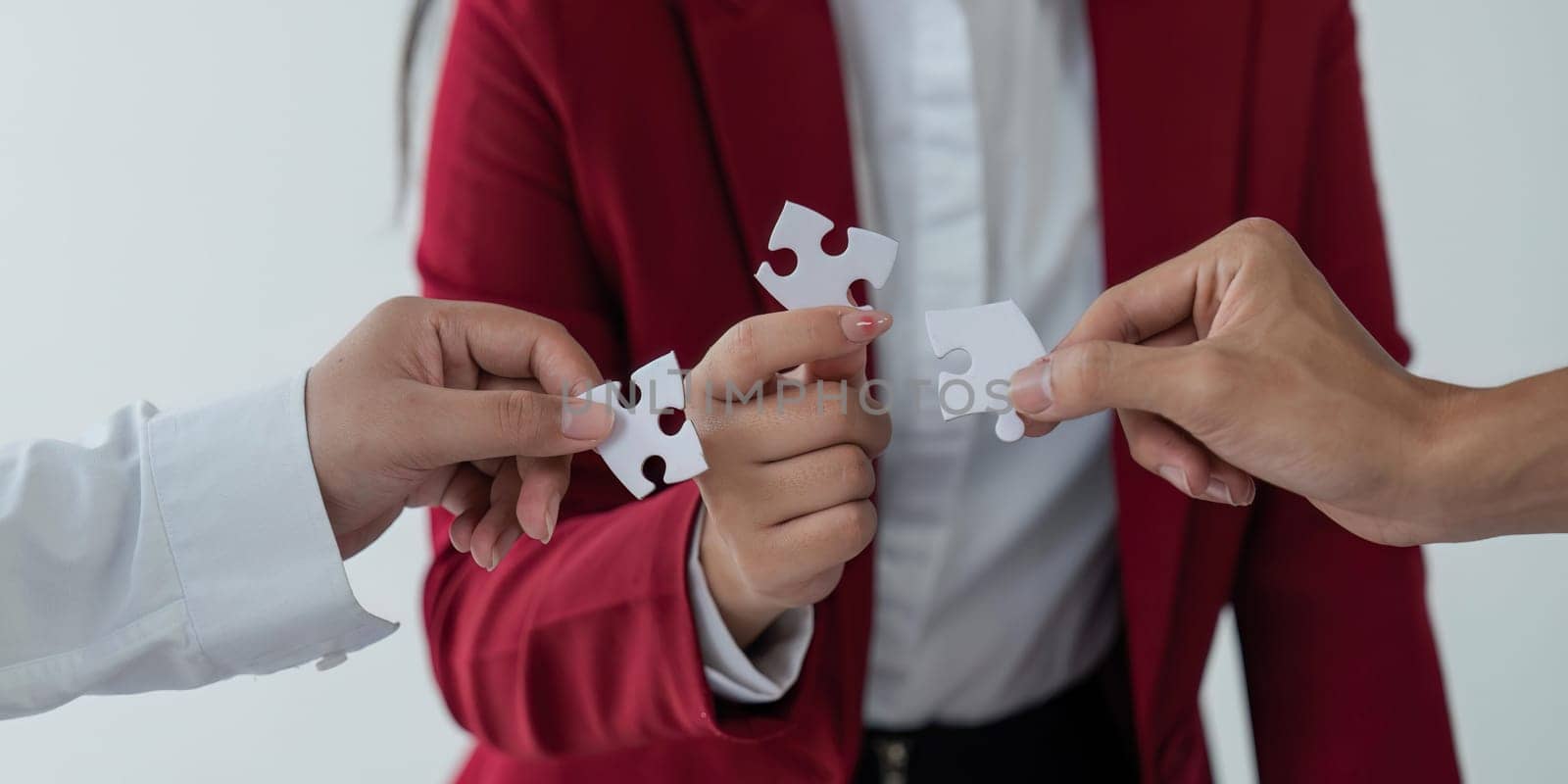 Concept of teamwork and partnership. Hands join puzzle pieces in the office. business people putting the jigsaws team together. Charity, volunteer. Unity, team business by nateemee