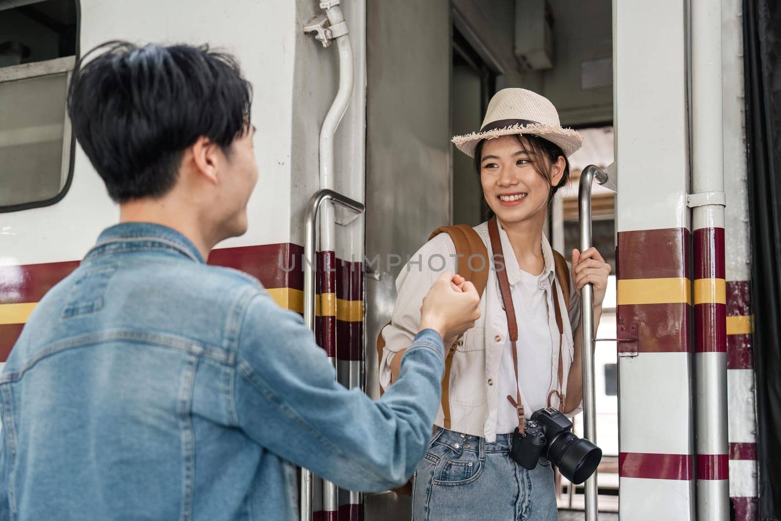 Happiness of young asian couple. A young man sends his girlfriend on a train.