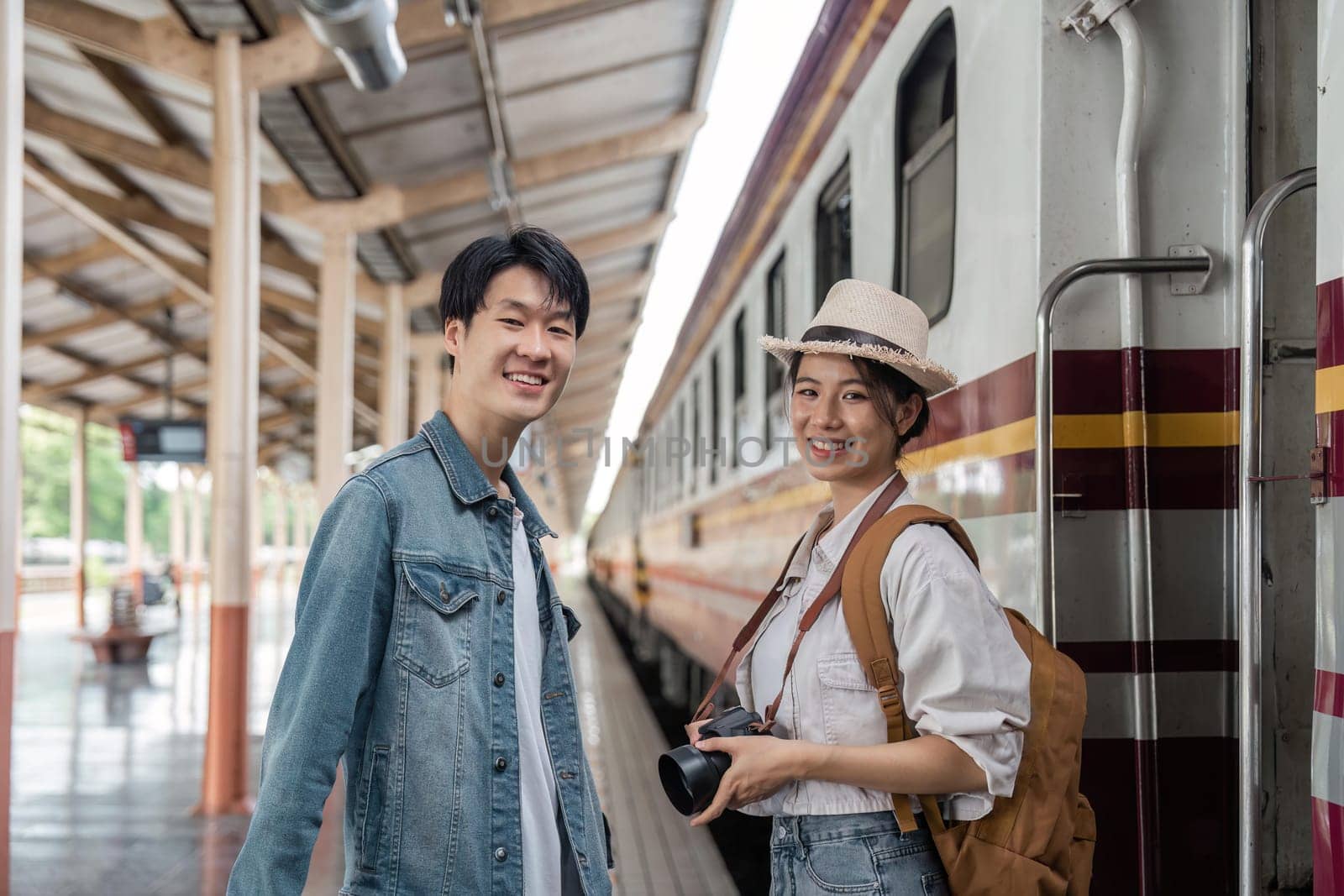 Asian couple travelers, backpack travelers, together at train station platform. tourism activity or railroad trip traveling concept.