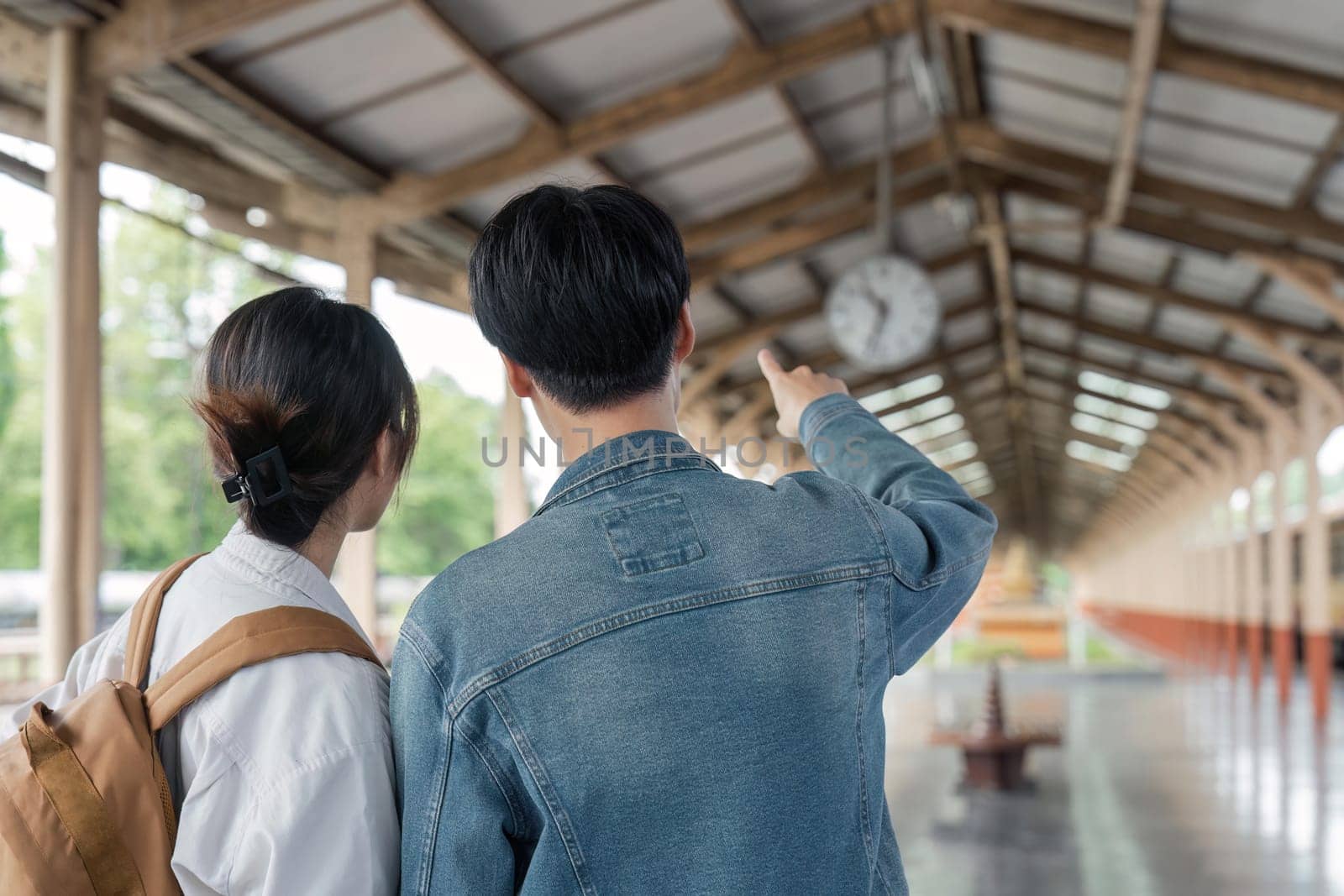 Asian couple travelers, backpack travelers, together at train station platform. tourism activity or railroad trip traveling concept.