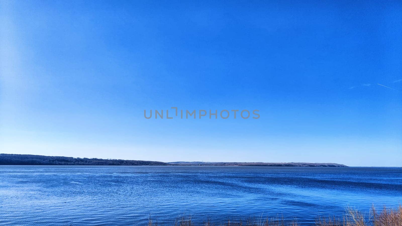 Beautiful blue water, sky and earth on the distant horizon. Natural landscape with water on sunny day. Background with landscape and copy space