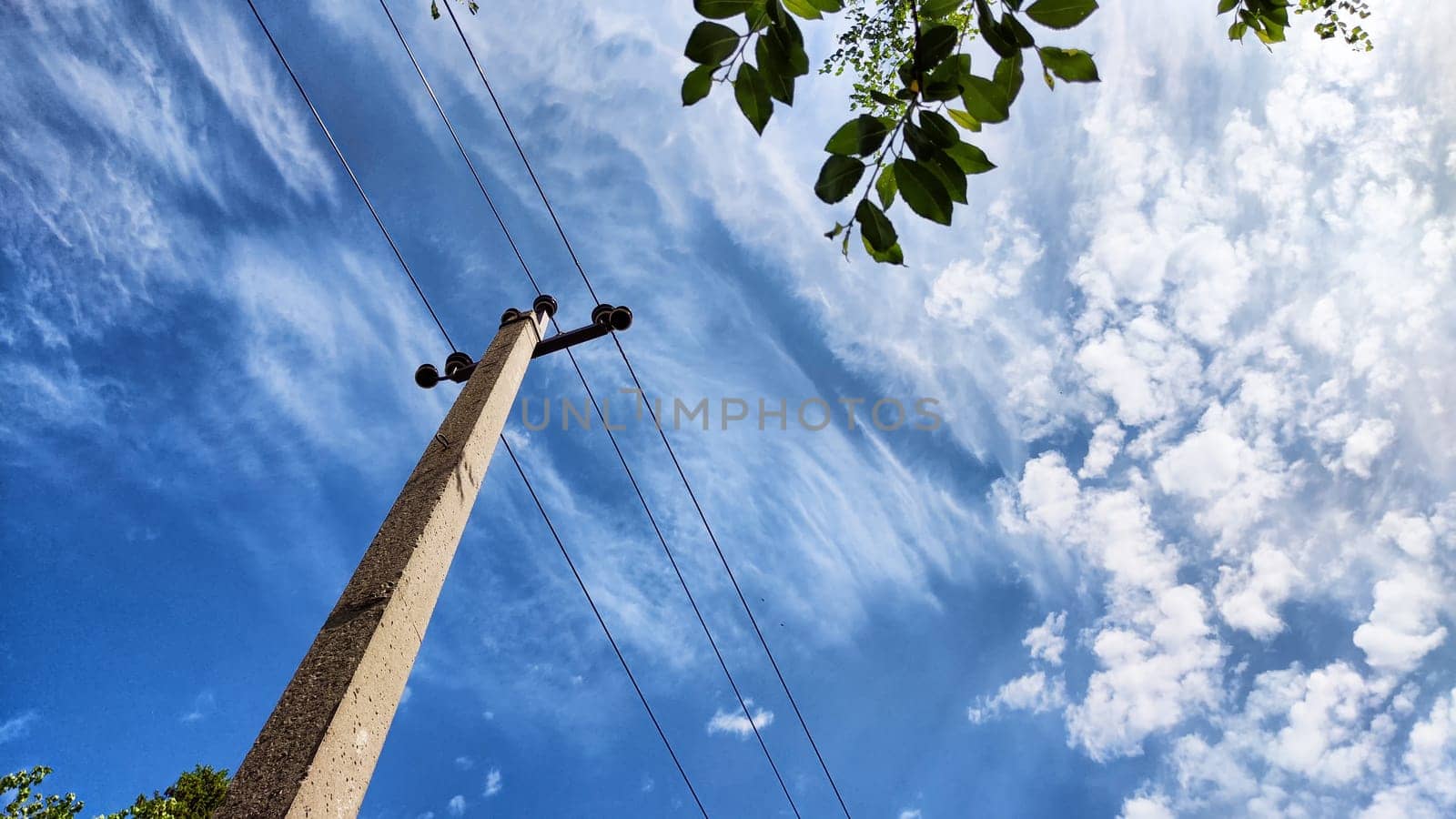 Closeup of old power poles on clear summer day. Old hight voltage electric pole with wires and blue sky with clouuds on background