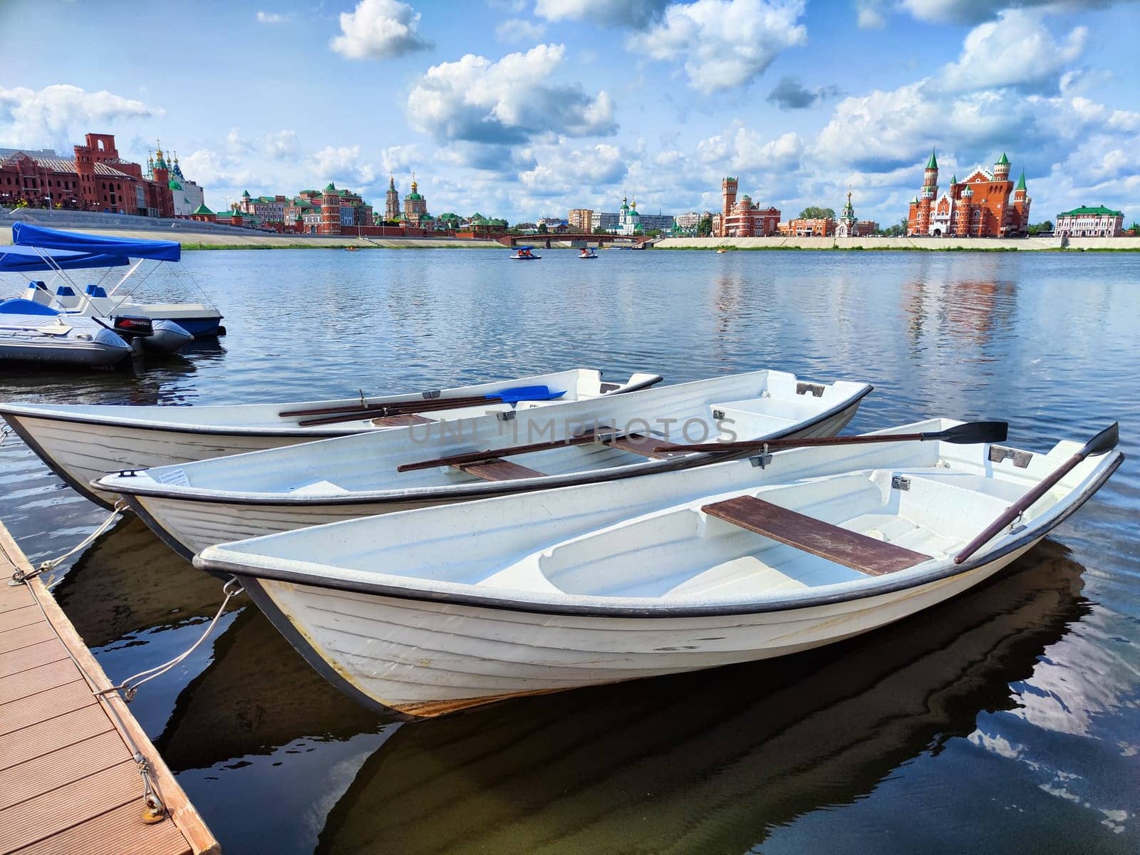 Harbor with wooden boats in city. Embankment of the resort town. Sunny summer day and water landscape in summer