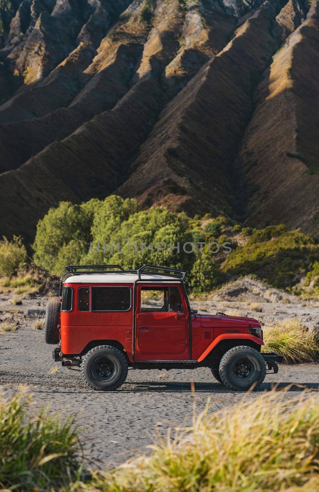 Close up view of red jeep with Bromo volcano background by Popov