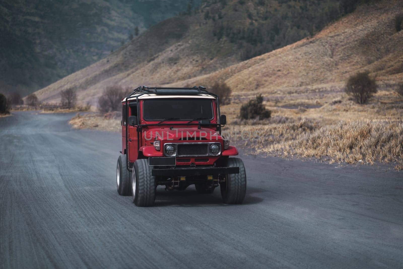 Close up shot of driving red jeep on Bromo road. Rental off road vehicle for exploring mountain volcano reservation
