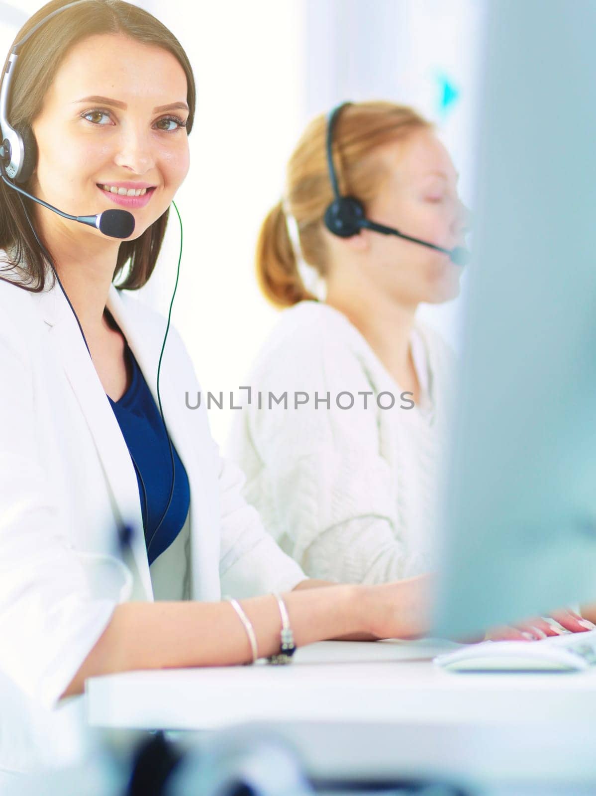 Smiling businesswoman or helpline operator with headset and computer at office.