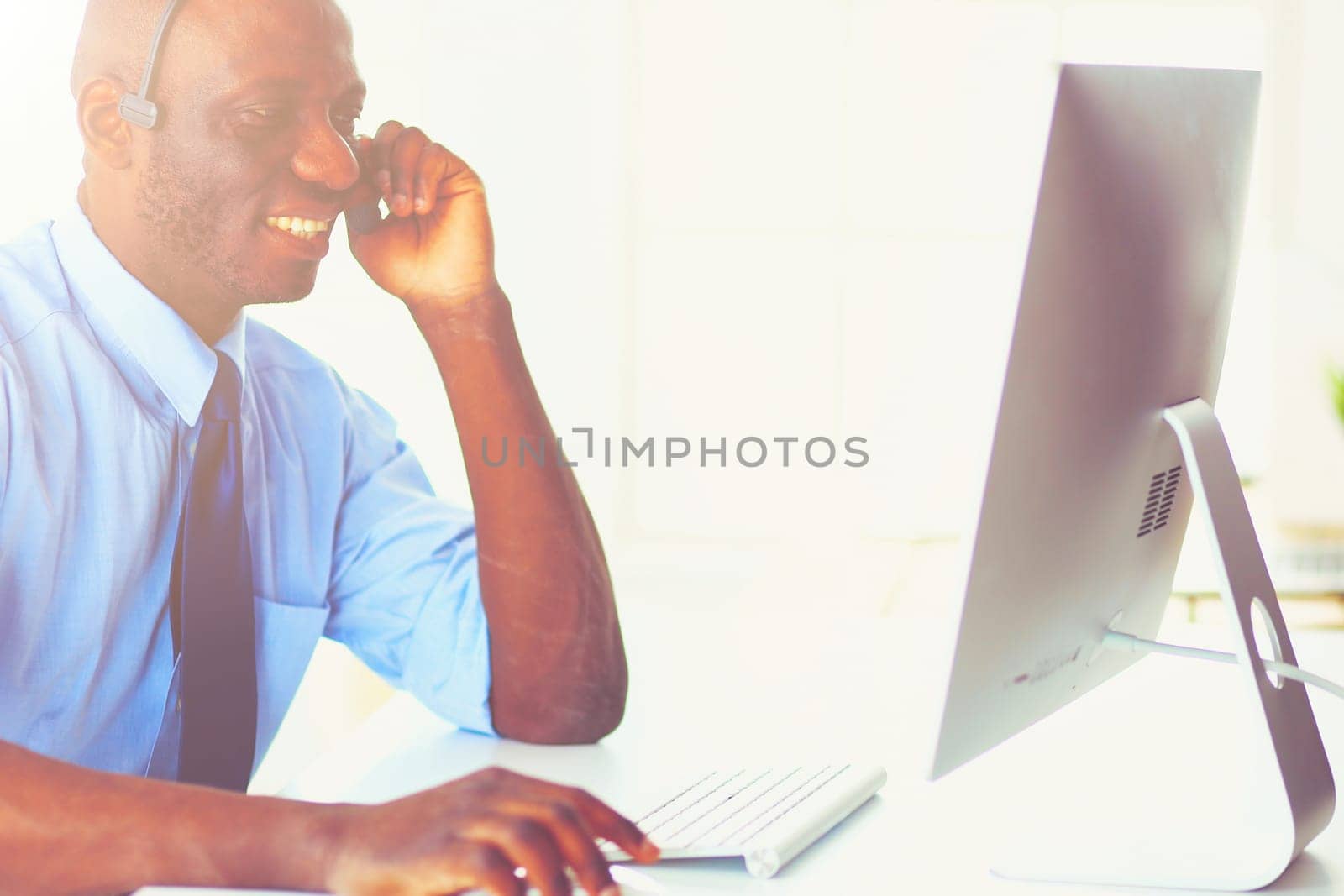 African american businessman on headset working on his laptop.