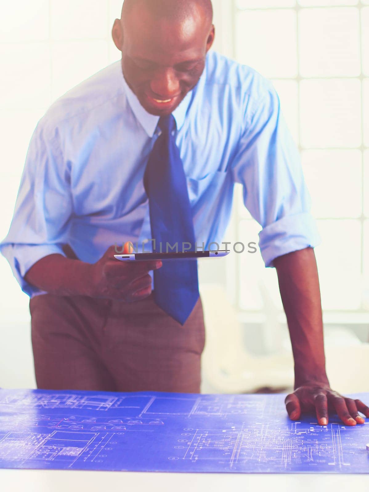 African american architect working with computer and blueprints in office.