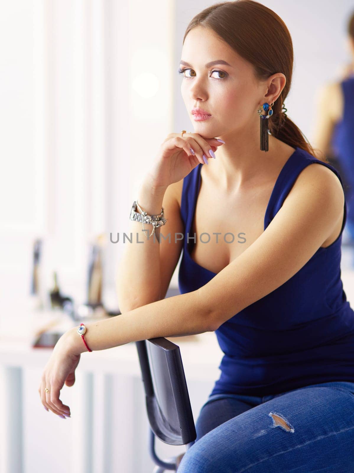 Young woman sitting on a chair isolated over white background.