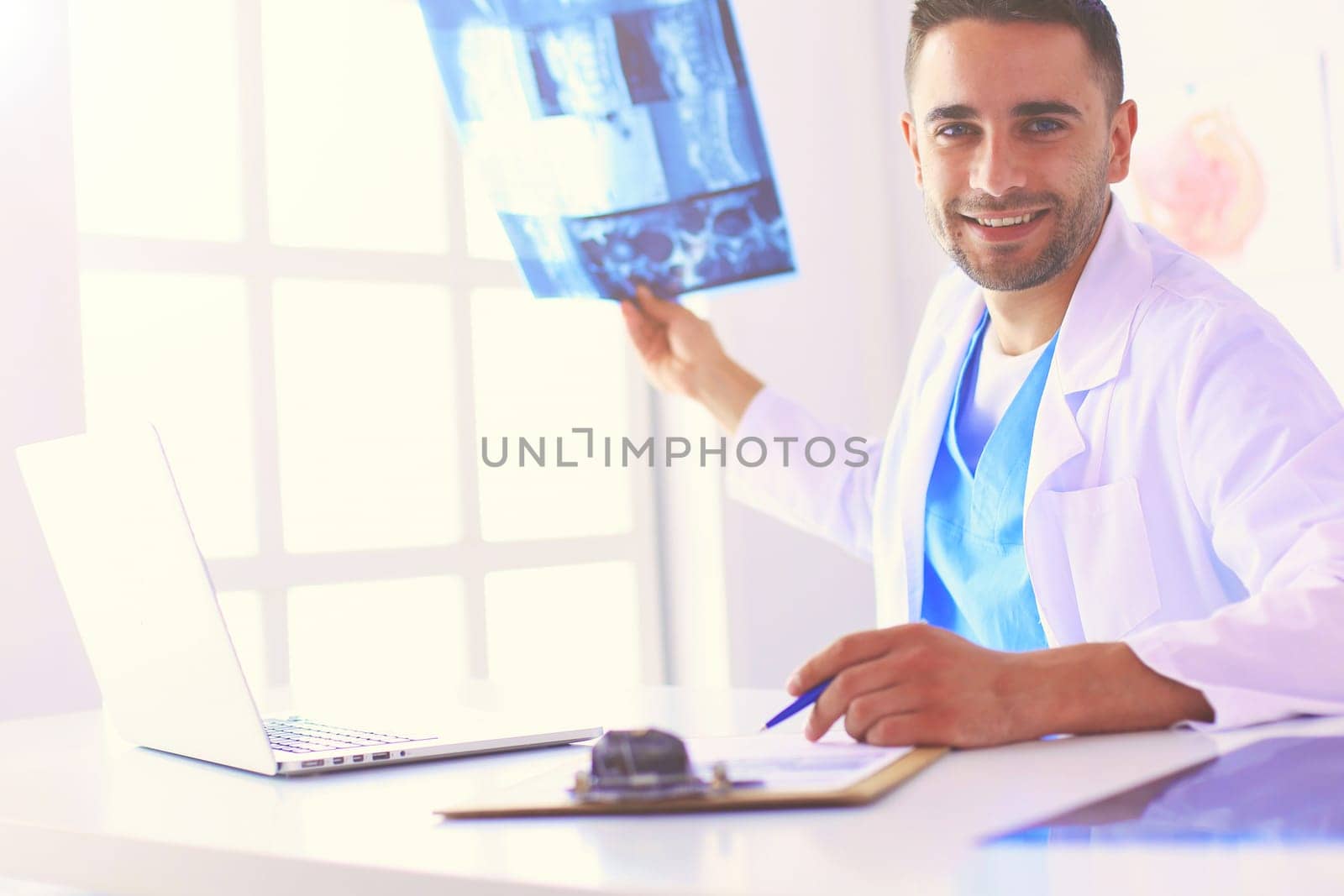 Handsome doctor is talking with young female patient and making notes while sitting in his office