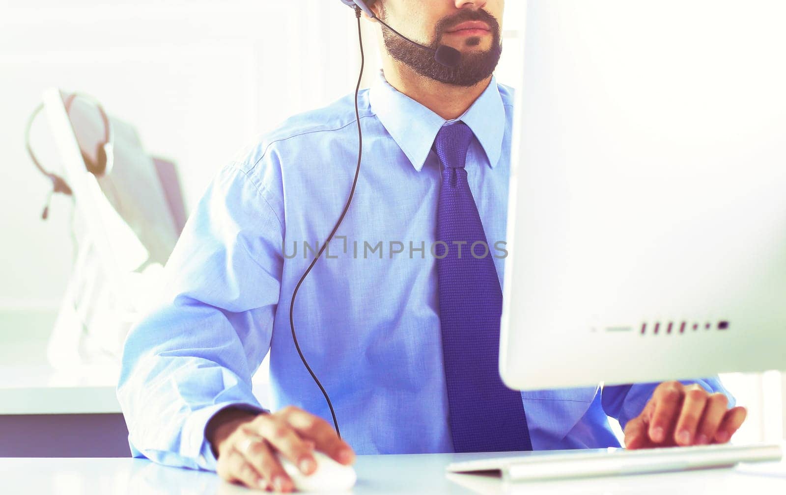 Businessman in the office on the phone with headset, Skype, FaceTime.