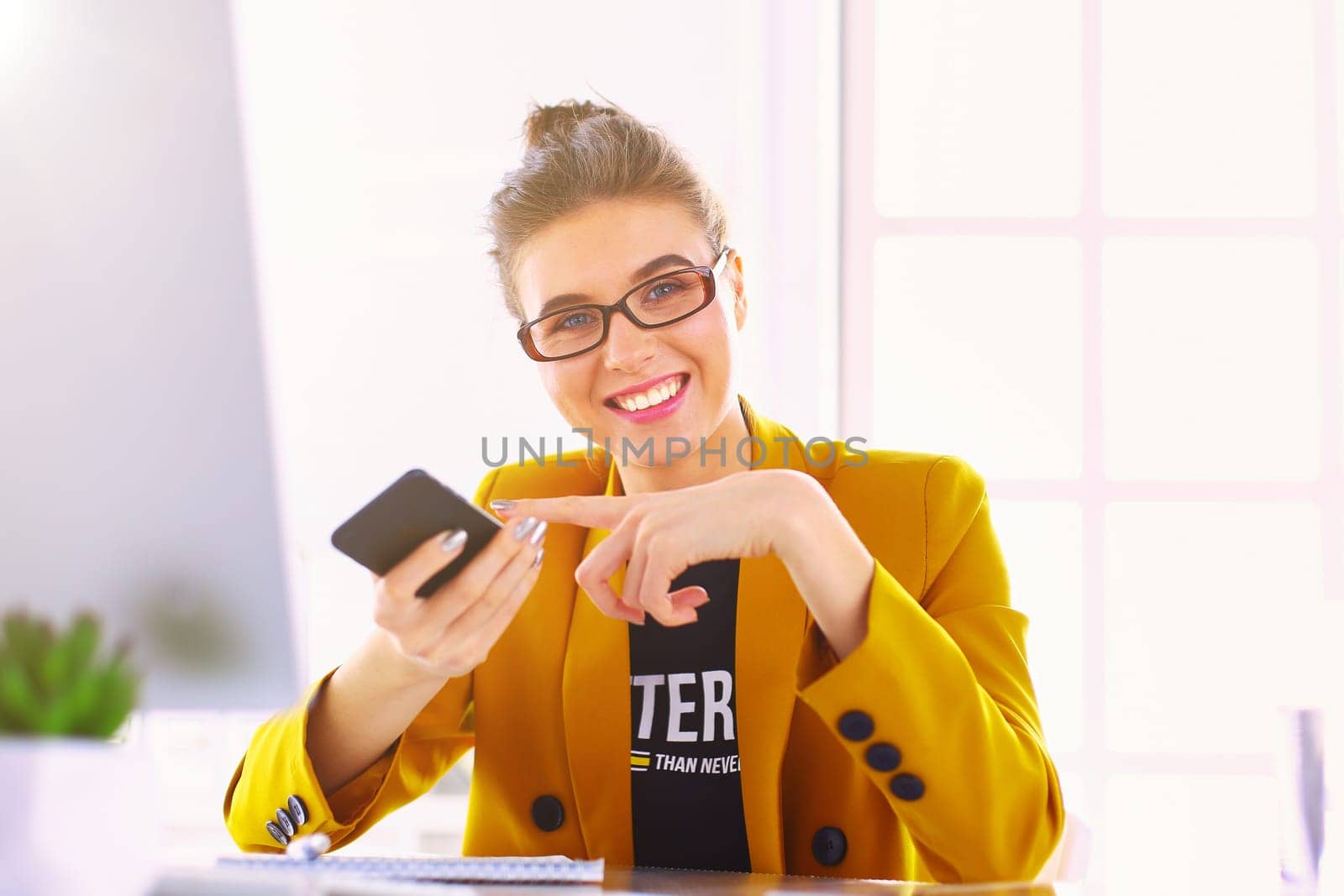 Businesswoman sitting in office with laptop on telephone.