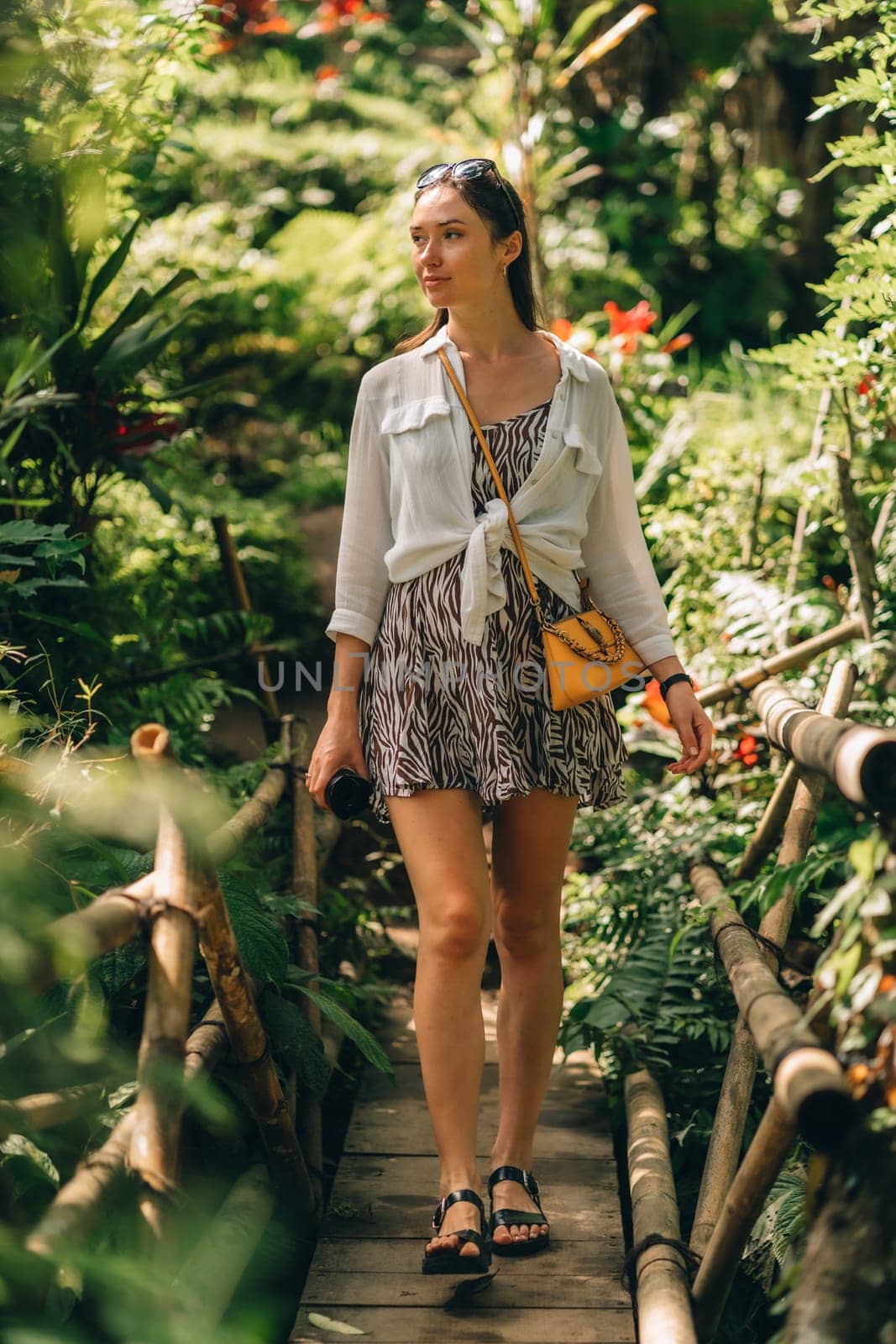 Front view of walking girl on wood bridge in jungle by Popov