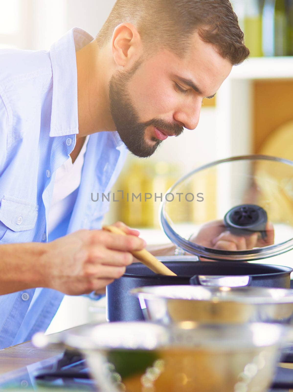 Man following recipe on digital tablet and cooking tasty and healthy food in kitchen at home.