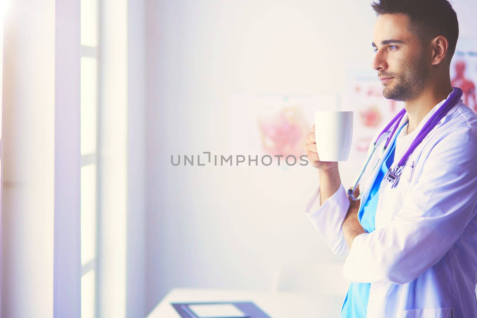 Young and confident male doctor portrait standing in medical office