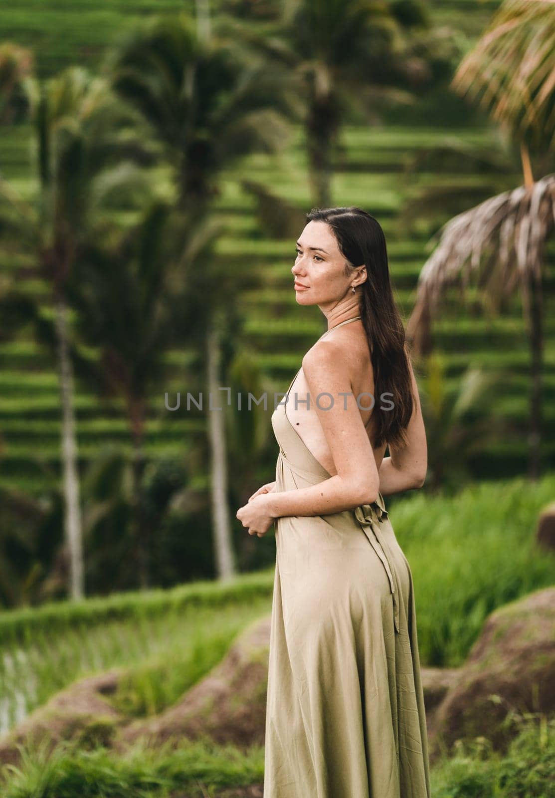 Stylish lady in green sexy dress on footpath rice terrace. Young elegant lady admiring evergreen balinese nature