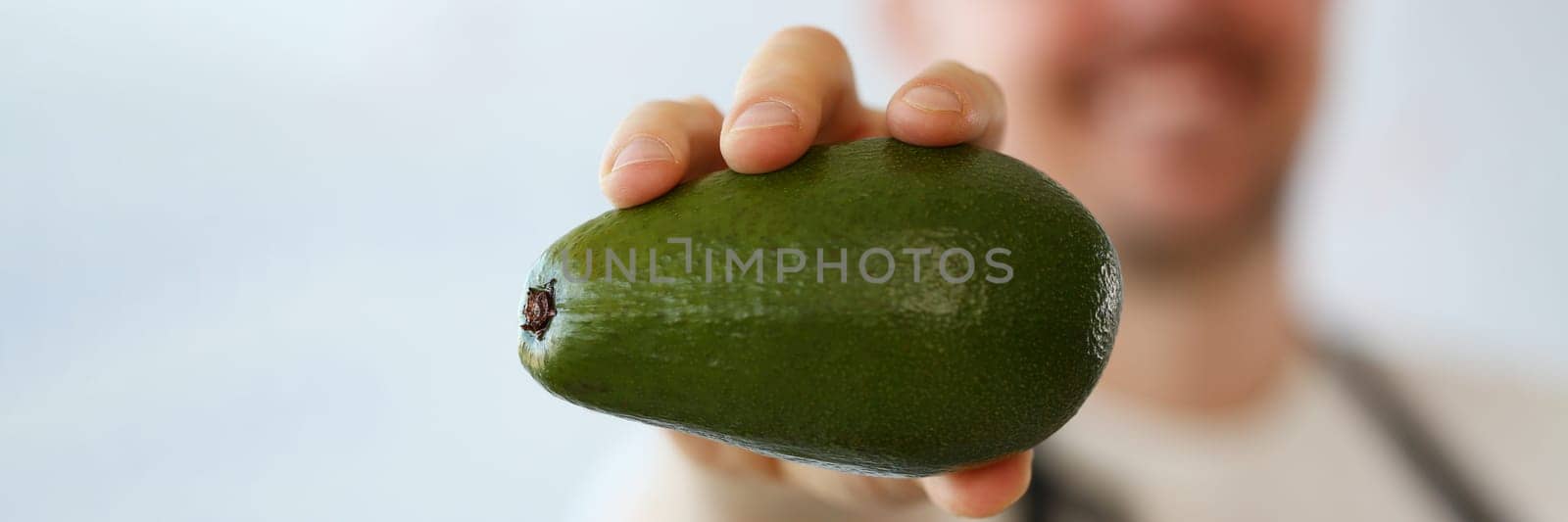 Cook holds fresh juicy green avocado in hands closeup by kuprevich