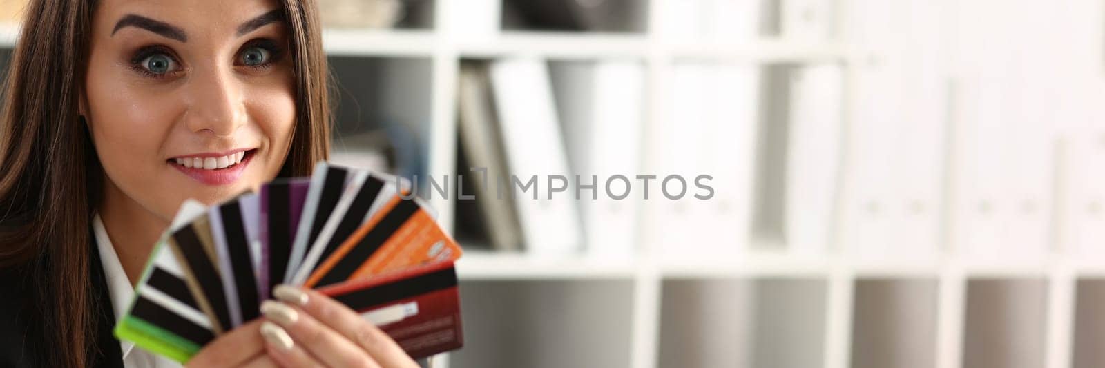 Portrait of young beautiful woman holding bank plastic credit cards. Choice of banking services and approved loan