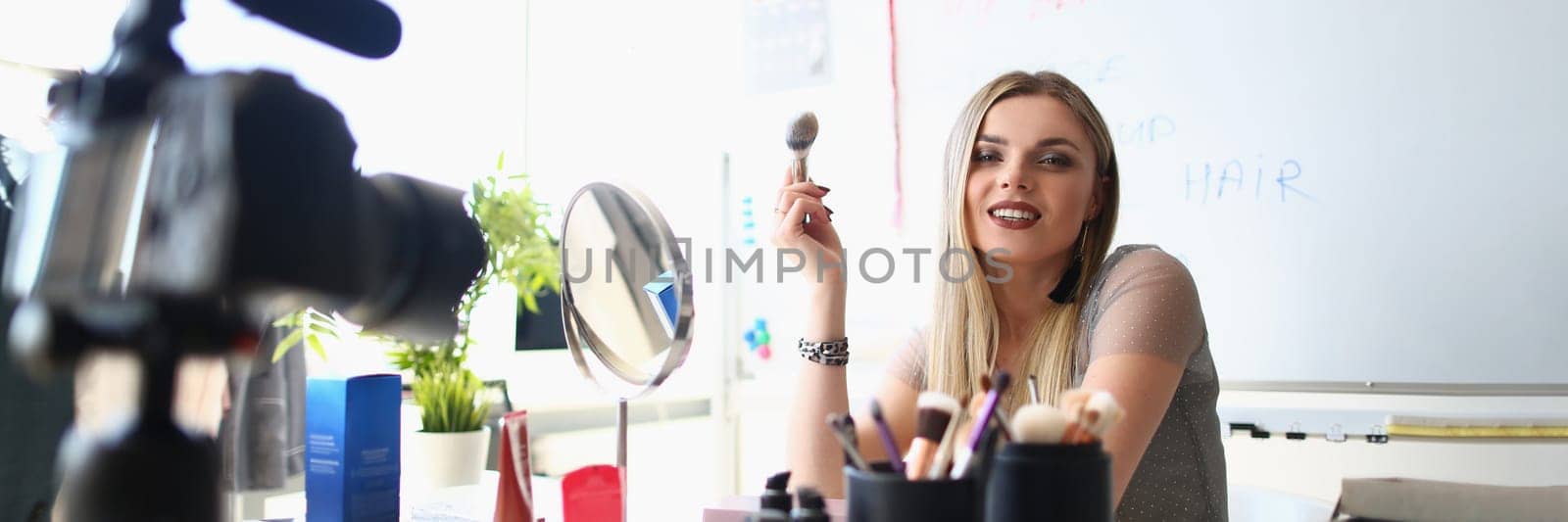 Beautiful woman blogger shows how to apply makeup and use cosmetics. On camera to record beauty vlogs live at home
