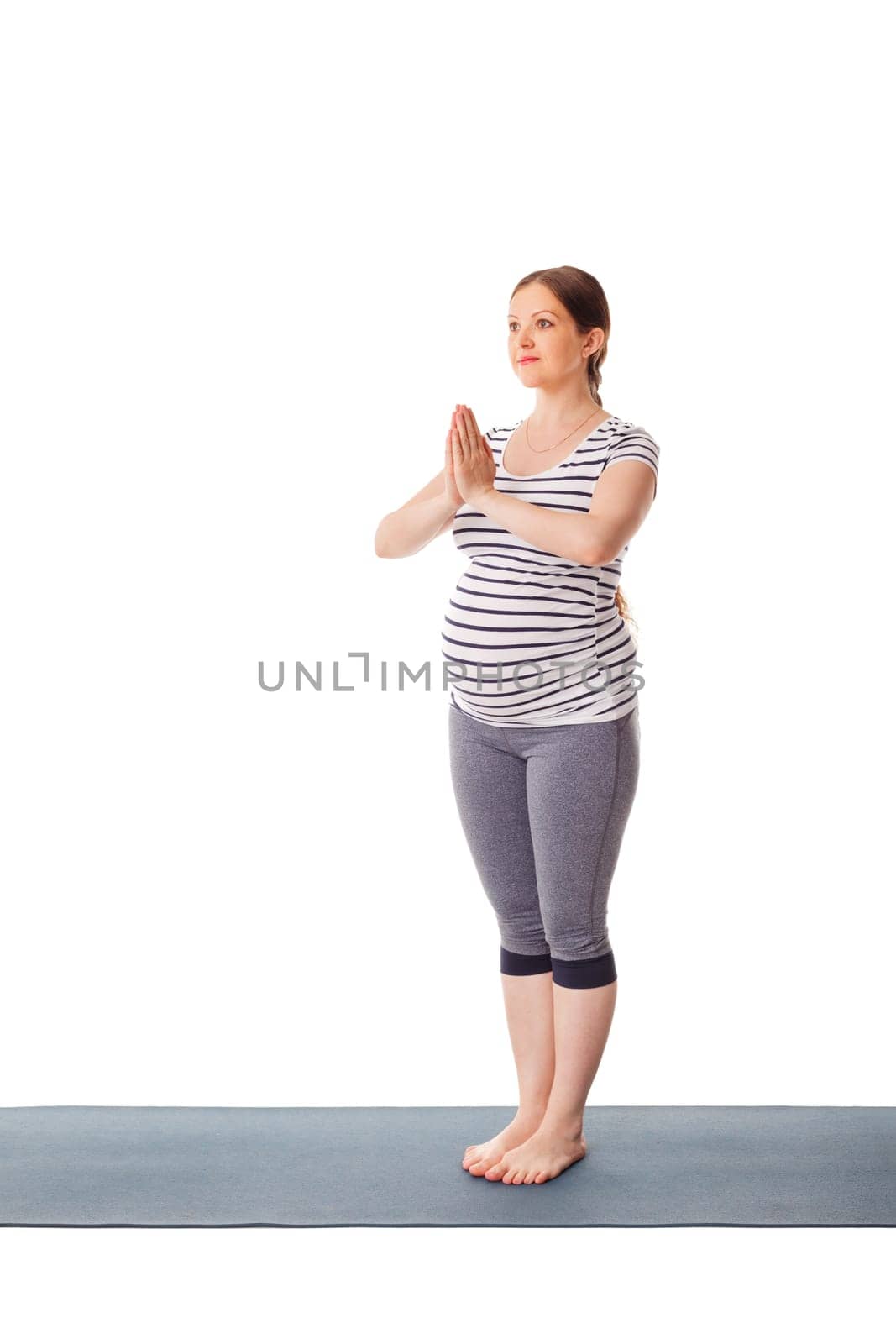 Pregnancy yoga exercise - pregnant woman doing yoga asana Tadasana Mountain pose with namaste isolated on white background