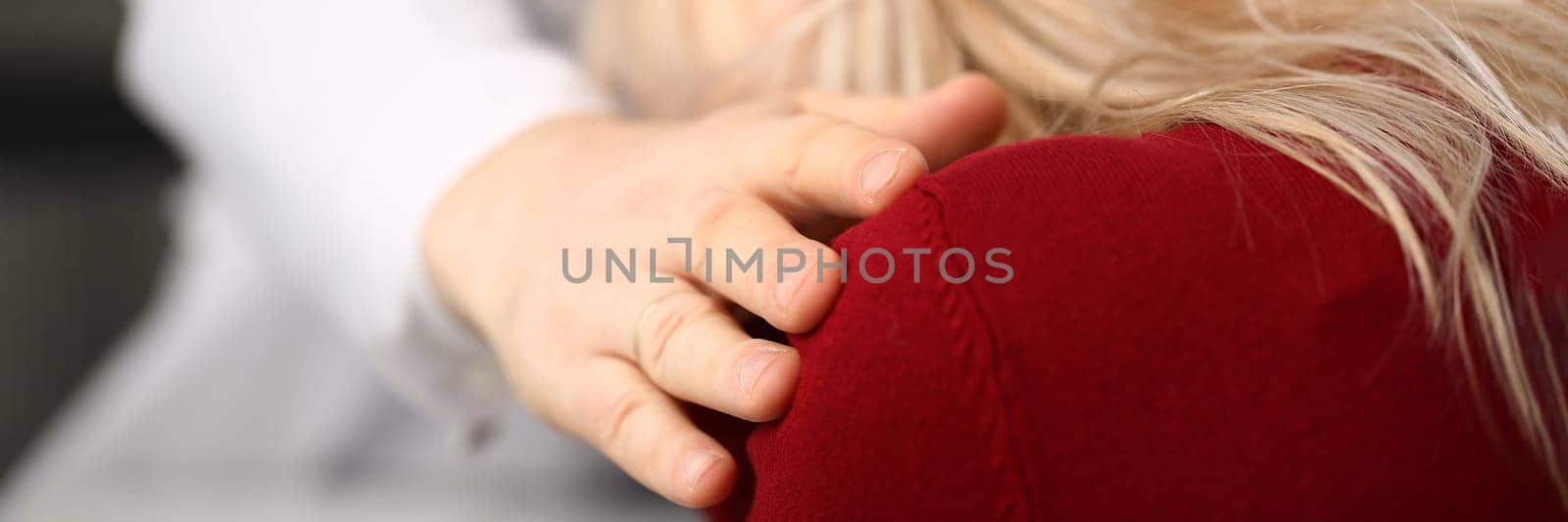 Doctor puts hand on shoulder of patient and sympathetically consoles by kuprevich