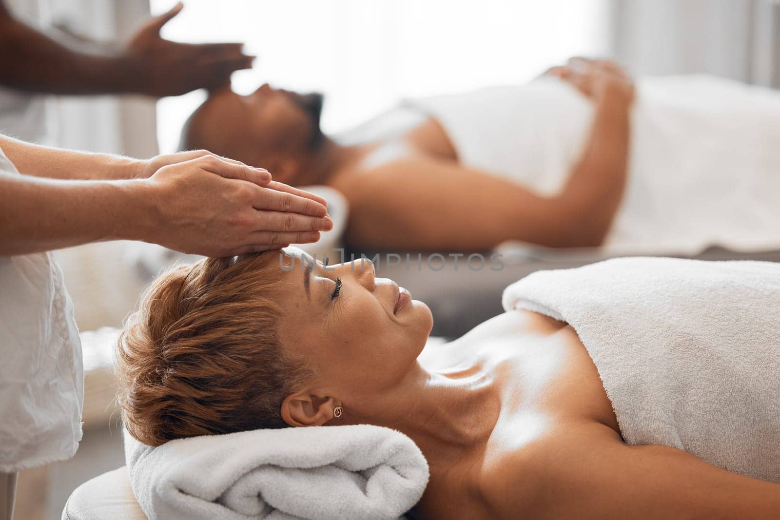 Woman, head and spa massage of couple at beauty salon, holiday resort and wellness vacation, face cosmetics and peace in Bali. Black woman, luxury facial and relax treatment from skincare therapist by YuriArcurs