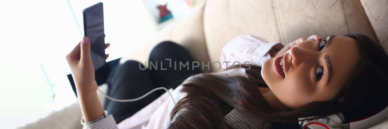 Relaxed woman listening to music on headphones at home by kuprevich