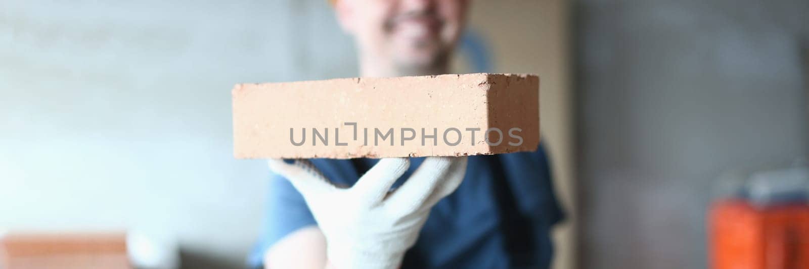 Master builder man holding red brick at construction site. Brick laying master concept