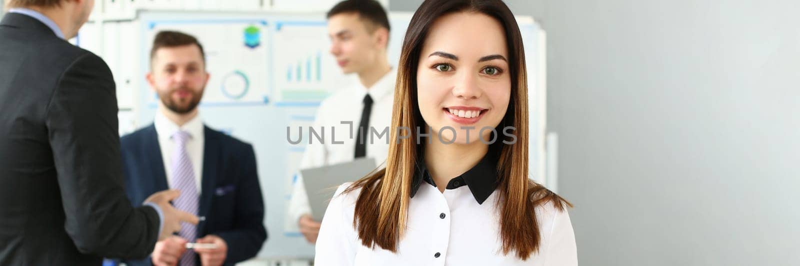 Portrait of a smiling businesswoman in background group of colleagues partners by kuprevich