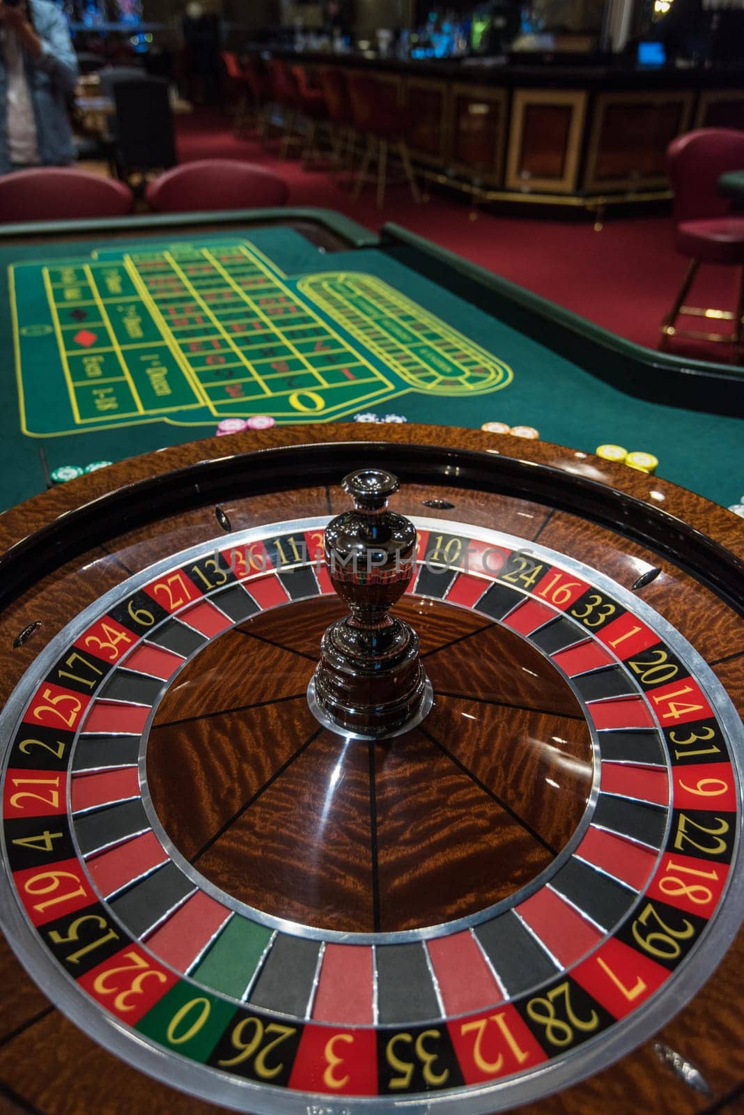 Casino, gambling and entertainment concept - roulette table and stack of poker chips