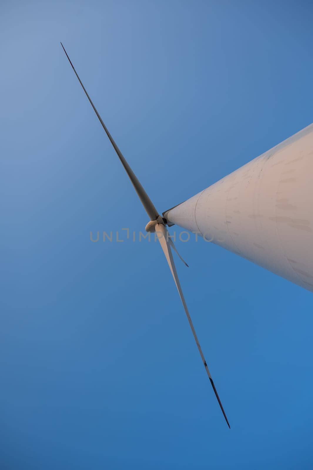Bottom view of a windmill against a blue sky. Alternative energy source