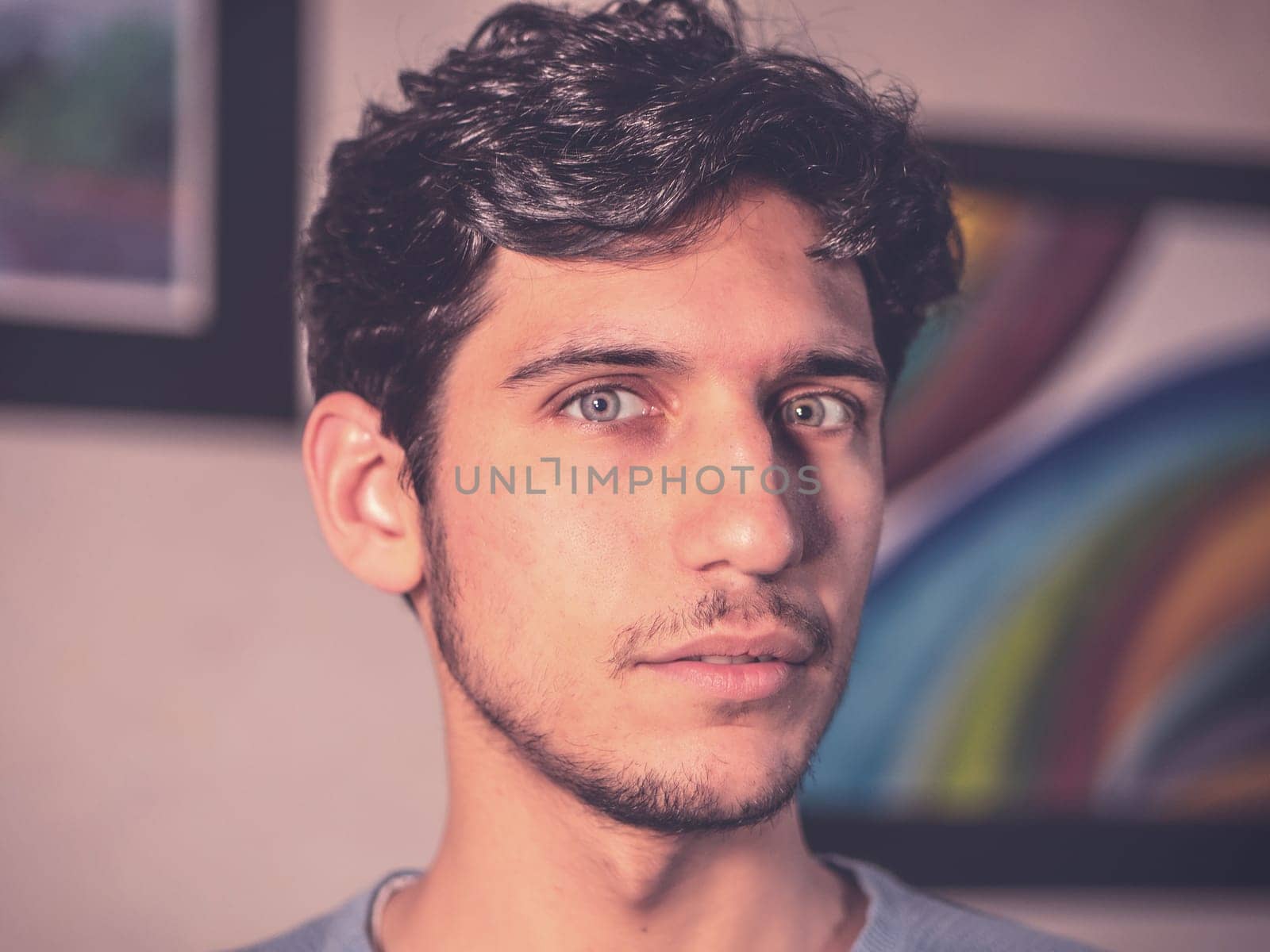 Handsome young man with serious expression at home, looking at camera