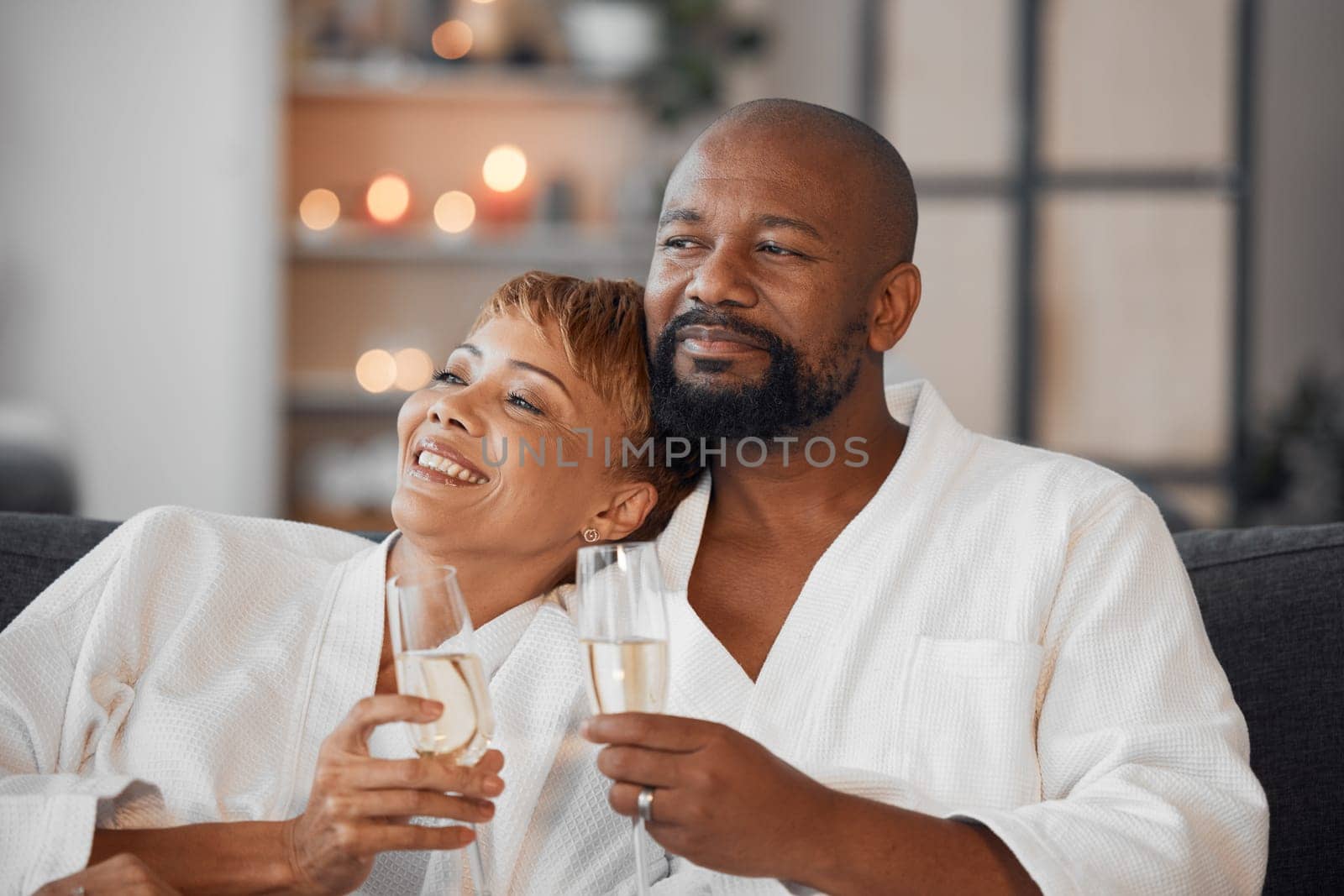 Spa, couple and romance with champagne relax, happy together and calm bonding on sofa. Married man, woman smile and relationship wellness therapy on romantic honeymoon or relaxing vacation travel.